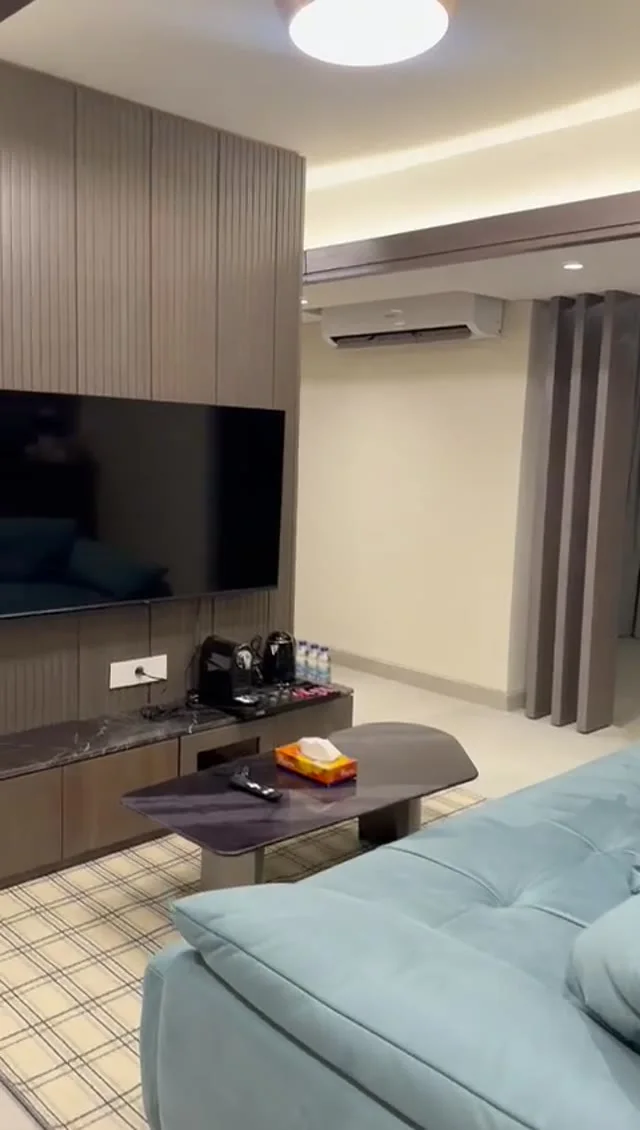 Suite 104 de The Stay : le salon avec canapé bleu et coin télévision, image extraite de la visite vidéo