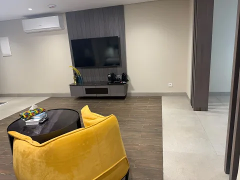 Studio 105 de The Stay : le coin salon avec fauteuil jaune et téléviseur