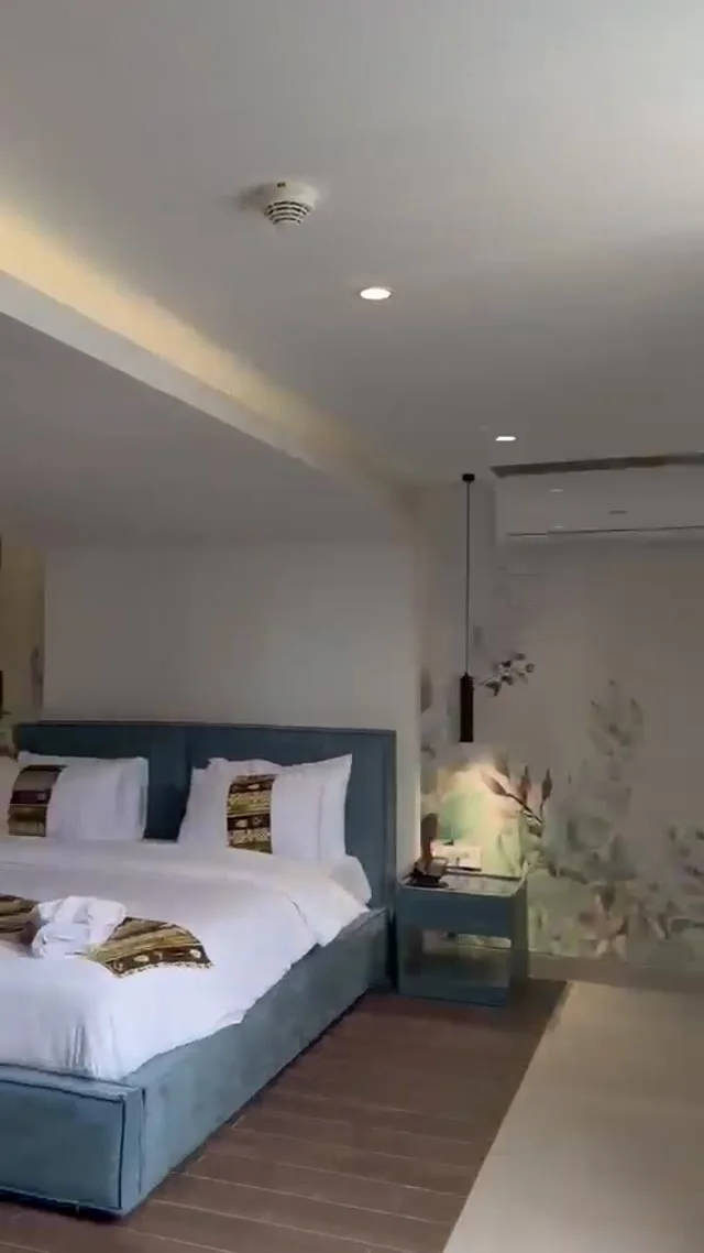 Studio 106 de The Stay : la chambre avec lit double et fauteuil jaune, image extraite de la visite vidéo